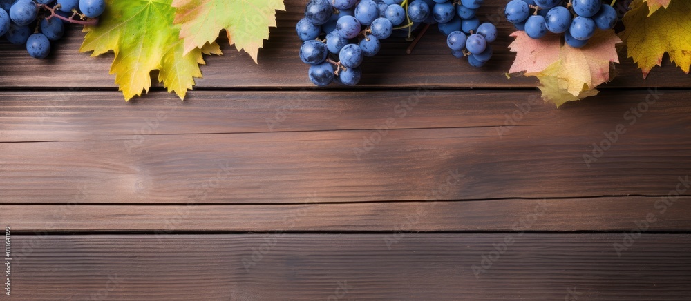 Poster A top down view of blue grapes and vibrant grape leaves on weathered wooden table creating a captivating background for copy space image