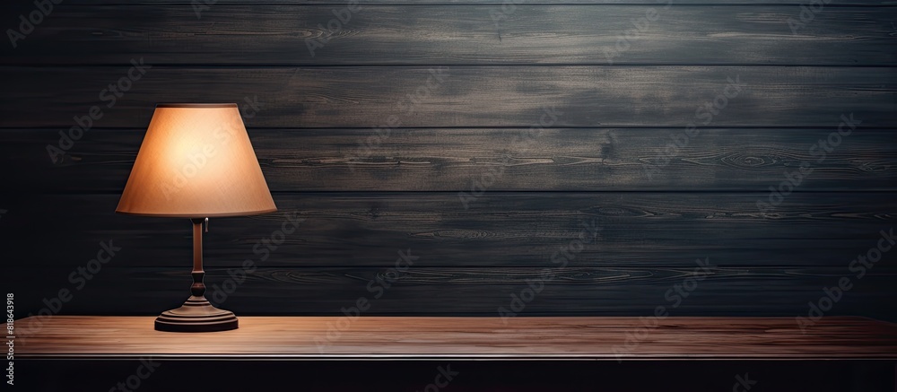 Poster dark room with a wooden table featuring a glowing lamp providing ample copy space image