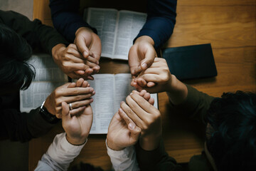 Christian Family prayer and worship. Christian group of people holding hands and praying worships to believe and Bible on a wooden table prayer meeting concept. Church Community pray together