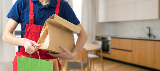 Courier holding paper bags with food, space for text. Delivery service