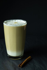 Latte coffee in glass near cinnamon stick on grey 