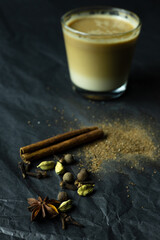 Spices near blurred glass of coffee with milk on grey background