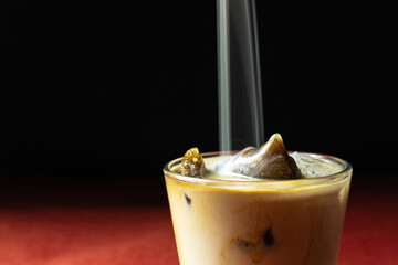 Long exposure of milk pouring in glass with iced coffee on black and red background
