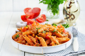 Classic italian pasta penne arrabbiata with vegetables on white wooden table. Penne pasta with...