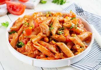 Classic italian pasta penne arrabbiata with vegetables on white wooden table. Penne pasta with sauce arrabbiata.