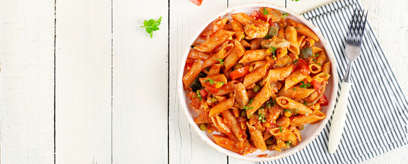 Classic italian pasta penne arrabbiata with vegetables on white wooden table. Penne pasta with sauce arrabbiata. Top view, banner