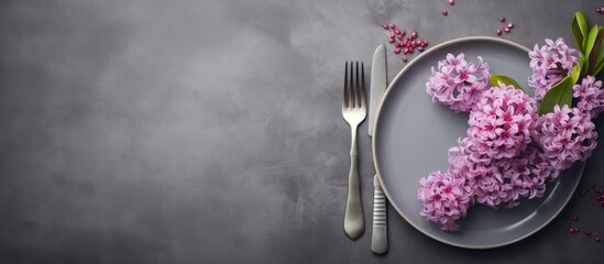 Copy space image of a hyacinth flower adorning a clean plate accompanied by cutlery set against a charmingly grungy grey backdrop