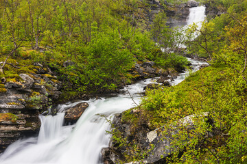 Stunning Waterfall Cascading Through Lush Forest in Lappland, Sweden During Spring