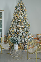 Home New Year's interior in white and gold colors.  Christmas tree with gifts, decorated with garlands. Cozy atmosphere of a home holiday, classic design