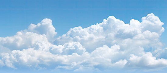 A nature background featuring puffy white clouds against a clear blue sky with copy space image available