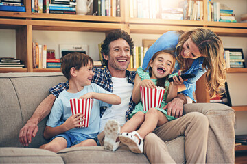 Happy family, watching tv and laughing with popcorn for funny movie, weekend or holiday on living...