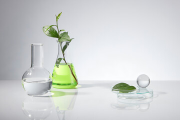 White color tones photo, a boiling flask with transparent liquid, erlenmeyer filled by green liquid...