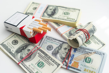white cigarettes lying on the dollar bills. concept of financial cost of smoking.
