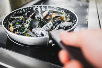 Close-up of fresh mussels being cooked in a pan, garnished with herbs