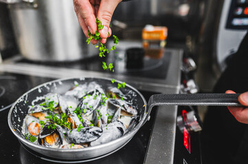 Close-up of fresh mussels being cooked in a pan, garnished with herbs