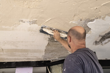 Builder applies plaster or cement to the ceiling. Suitable for renovation and construction concept