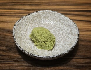 Wasabi in a small white ceramic dish is used mixed with soy sauce to be eaten with sushi and sashimi.Wasabi is a plant in the mustard family