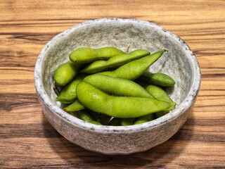 fresh green peas.Edamame in a white ceramic bowl on a wooden table.Beans are high in protein.