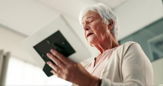 Senior woman, photo frame and sad in home with memory, thinking and mourning for grief in lounge. Elderly person, picture and depressed with ideas, remember and reflection in living room at house