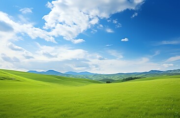 Obraz premium Green grassy hills with blue sky and mountains landscape background