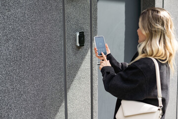 female entering secret key code for getting access and passing building using application on mobile phone, woman pressing buttons on control panel for disarming smart home system
