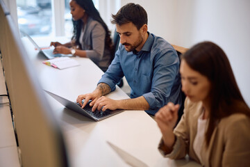 Young businessman using computer while working in shared workspace office.