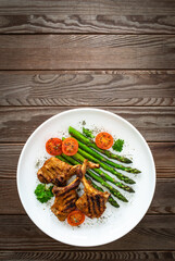 Lamb chops with bone and cooked green asparagus on wooden table
