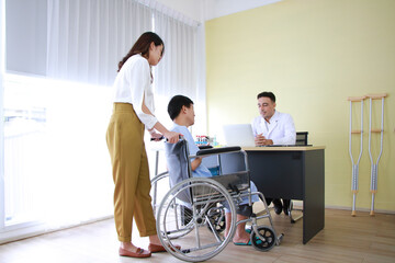 Fototapeta premium Asian woman is caring and take the elder old father sitting on wheelchair and illness health for to see a Caucasian doctor and Checked by Stethoscope at hospital in Thailand