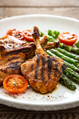 Lamb chops with bone and cooked green asparagus on wooden table
