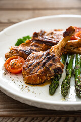 Lamb chops with bone and cooked green asparagus on wooden table

