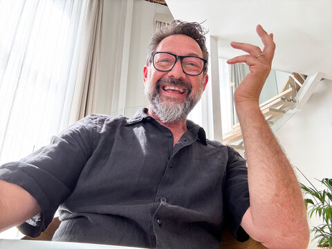 Cheerful adult having fun in videocall using laptop. Web camera view. Gesturing and smiling with friends online. Happy business solution. Modern worker video call team. Smart working happiness freedom