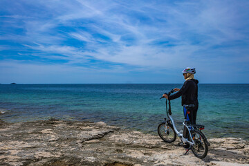 Cycling routes in Croatia woman in helmet riding electric bike on Adriatic Sea e-bike
