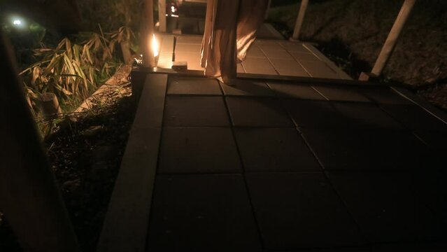 ランタンに照らされた木道を歩く女性