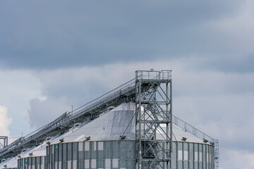 Obraz premium Granary elevator, silver silos on agro manufacturing plant for processing drying cleaning and storage of agricultural products, flour, cereals and grain. Large iron barrels of grain.