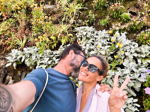 Happy couple middle age of tourist taking selfie picture together with leaves wall in background exploring city and destination. Traveler have fun in relationship. People and lifestyle with love