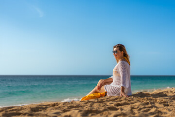 Beautiful woman sitting and sunbathing on sunny beach 
