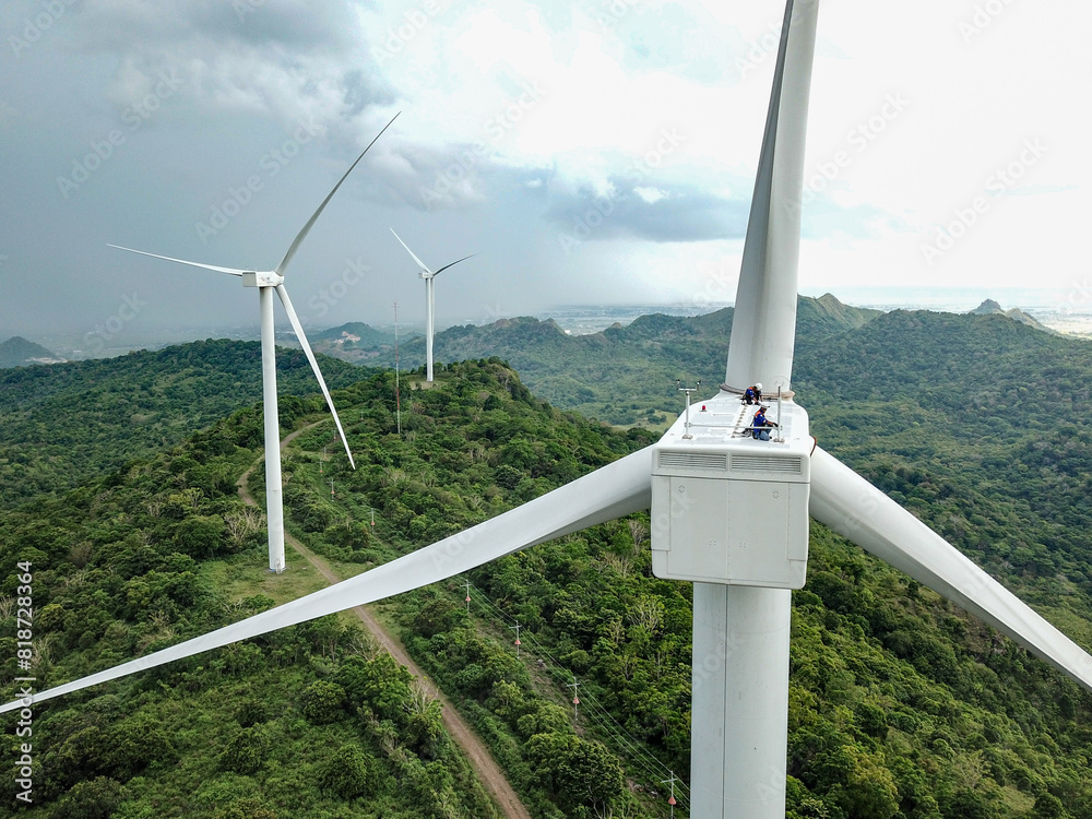 Wall mural wind turbine technicians work on the nacelle of a turbine in the wind farm area.