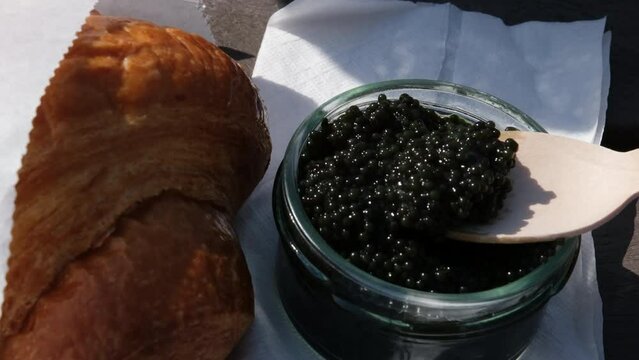 Collect black caviar from a jar, place it on a piece of wood, and eat it. Food on the street Picnic