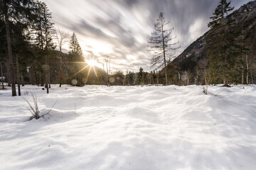 the sun shines brightly through the clouds behind some snow