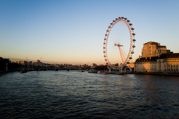 a ferris wheel that is in the water with some buildings in the background