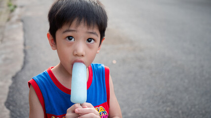 Portrait of a four years old cute Asian boy enjoying ice cream in summer, the small kid has fun...