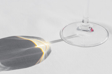 close-up of wine glass shadow on white tablecloth