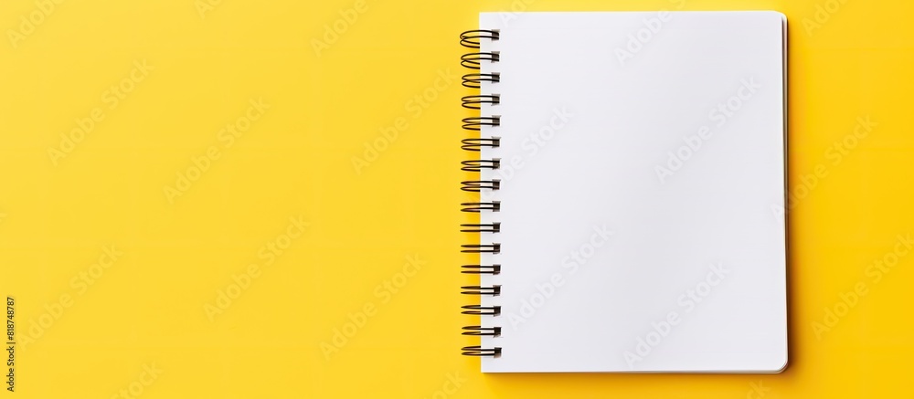 Aufkleber Top down view of a yellow background with a spiral notepad featuring white pages and ample copy space for adding images or text