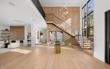 an open, modern home is shown with stairs and a curved glass table