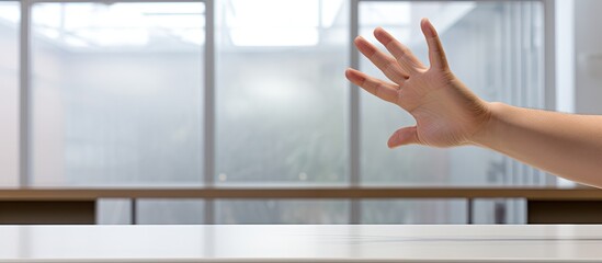 A hand held up against tables in an office cafeteria providing a close up view on a white background Copy space image