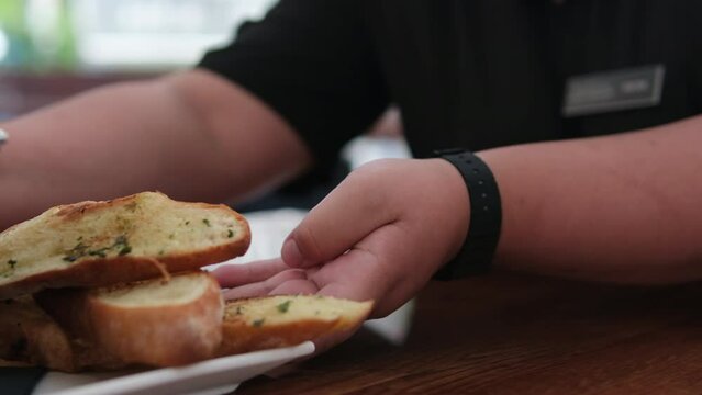 The waiter serves a black pan with croutons, croutons, delicious food, soup, serving on the table. Serving mussels