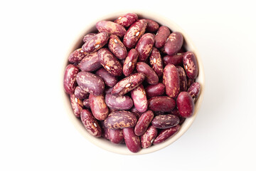 Uncooked, variegated kidney bean seeds in bowl on white background. Top view