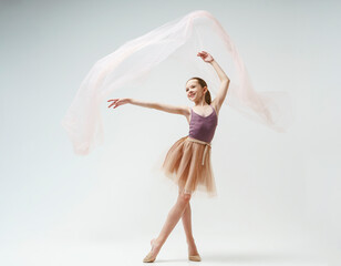 young teenage ballerina girl shows elements of dance with fabric in a photo studio