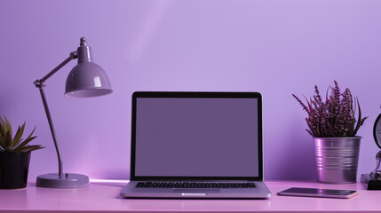 A laptop sits on a desk with a purple background. The laptop is open and the screen is blank. A potted plant sits next to the laptop, and a cell phone is on the desk