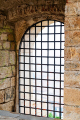 arched stone window with iron bars overlooking city, rustic and historic architectural element